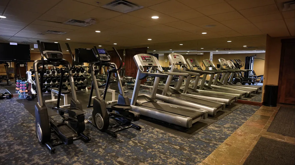 A bright, energetic fitness center outfitted with treadmills, elliptical machines, and free weights. Natural light fills the space, and modern equipment is neatly arranged for easy access, inviting guests to pursue their workout routines or join a group class.